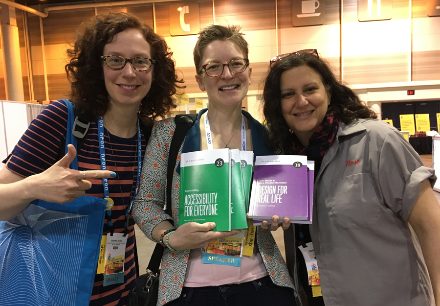 Johanna Bates, Eileen Webb, and Rose Liebman standing together, smiling, holding books "Accessibility for Everyone" and "Design for Real Life"