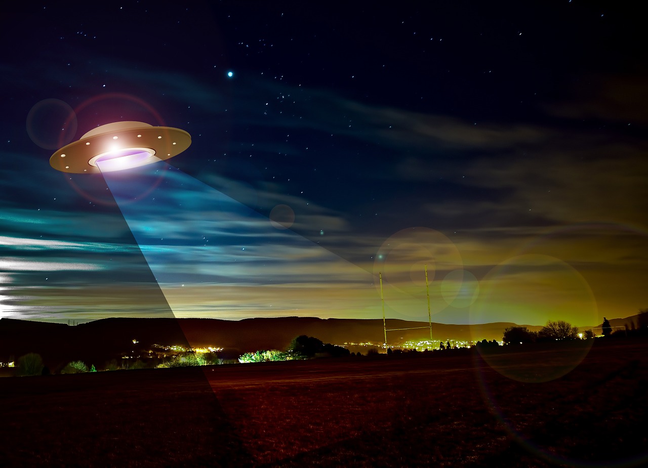 An illustration of a UFO spaceship at night, shining light onto an Earth landscape below.