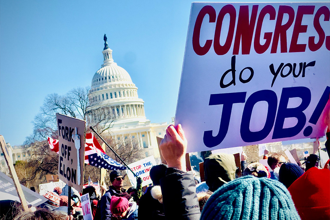 people outside the US capitol holding signs and flags